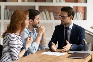 A man and woman sitting next to a lawyer discussing estate planning.